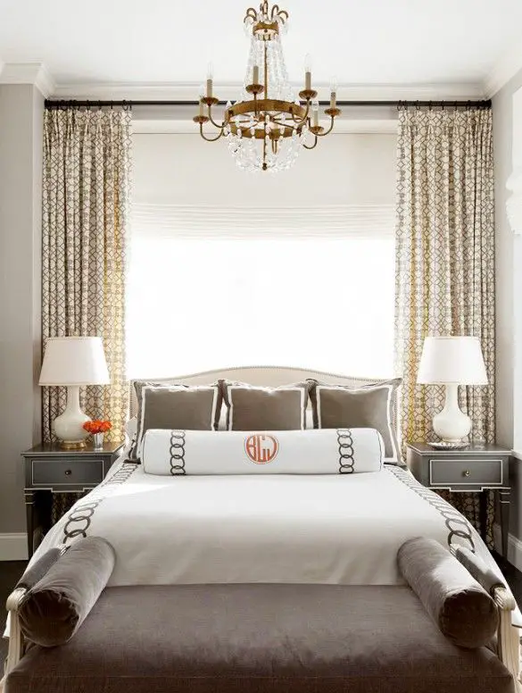 Big open window, white lamps, grey furniture, small chandelier and monogrammed bedding: 