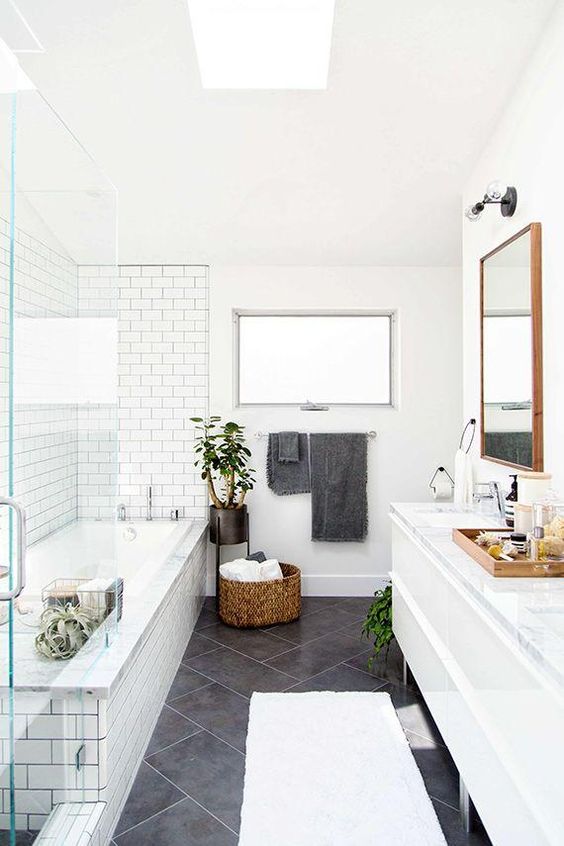 Love this large charcoal gray diagonal tiles on the floor paired with the white subway tiles and gray grout in the shower. Such a fresh look with the modern white cabinets and wood mirror!: 