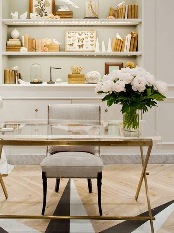 Glass and golden desk, grey chair, decorated shelves, white flowers: 