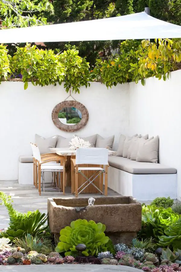 Outdoor entertaining nook- even this muted color/design still plays to a sea-like escape w/plant choices, coral, & a port-like mirror