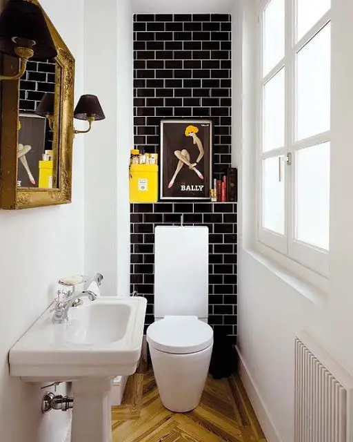 Tiny powder room with black Subway Tile and white grout. Herringbone floors.