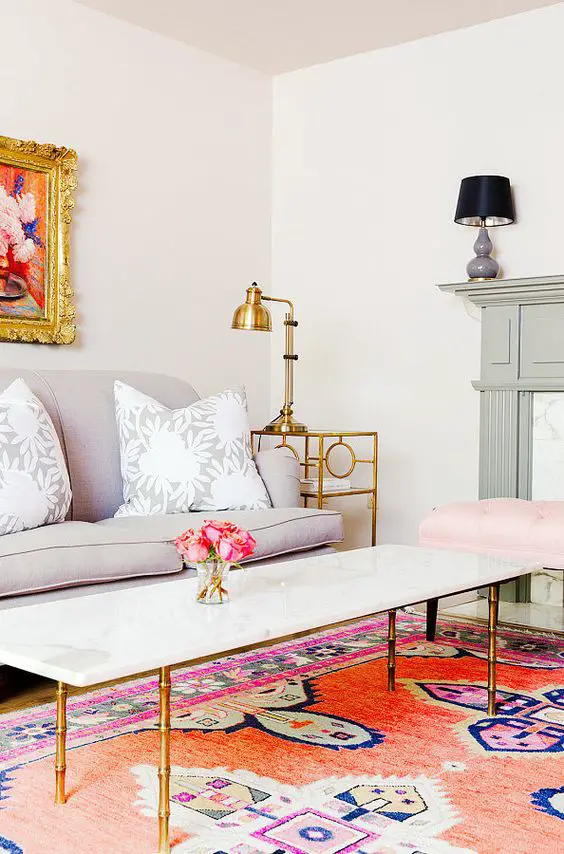 A colorful living room with feminine flair, marble coffee table with gold accents, and Persian rug: 
