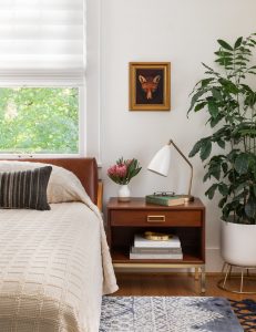 Bedroom with bed, picture and night stand with light, flowers in vase and books