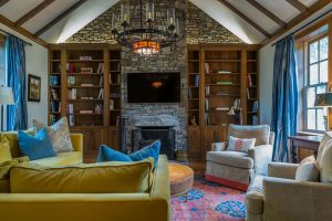 Cozy living room with green couch, rug, chairs, bookshelf and chandelier