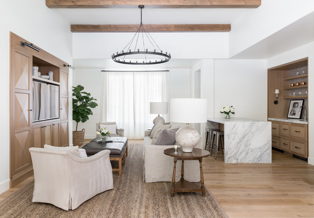 Living room with round chandelier, chairs, book shelfs, bar table