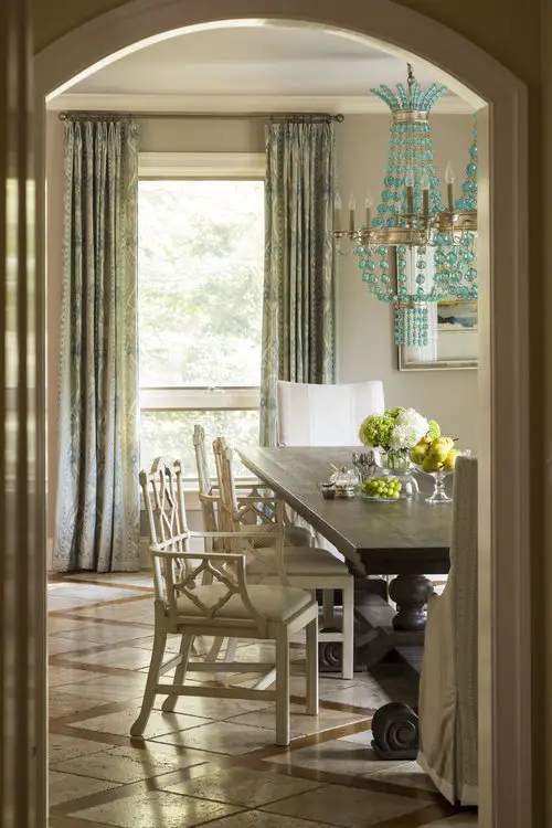 Look from hall into dining room with table, chairs and big window with curtains