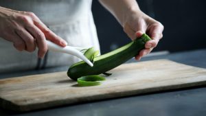Woman pealing cucumber, how food waste can cause a clogged drain