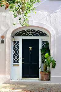 Decorated house exterior with door, and windows besides the doors and a pot plant in front of the house