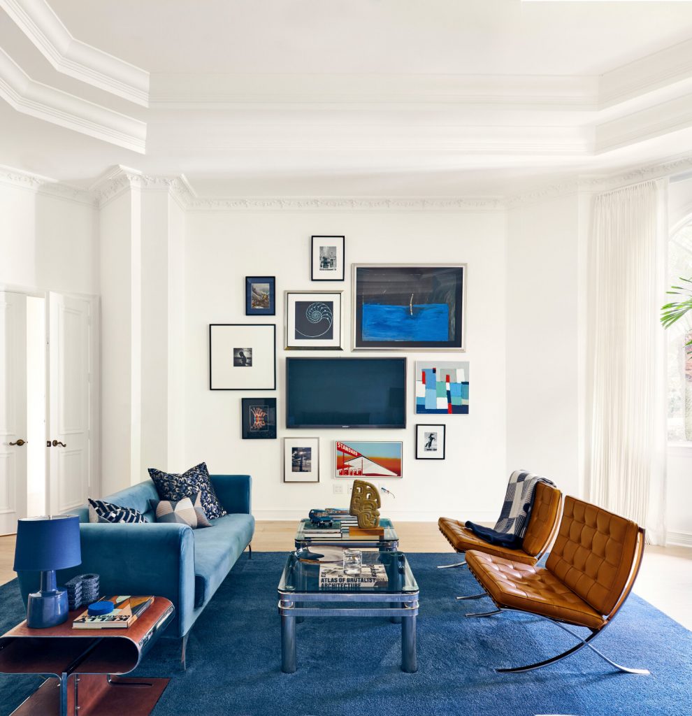 Blue and white living room with sofa, table, chairs and TV on the wall in the background