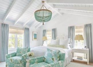 White and blue designed bedroom with king size bed, chandelier and two armchairs in front of the bed