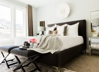 Bedroom with big white and black bed and chair with vase and flowers on it