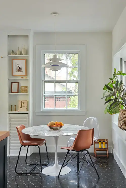 Dining room with round table and three chairs around it in the corner of the room beside the window
