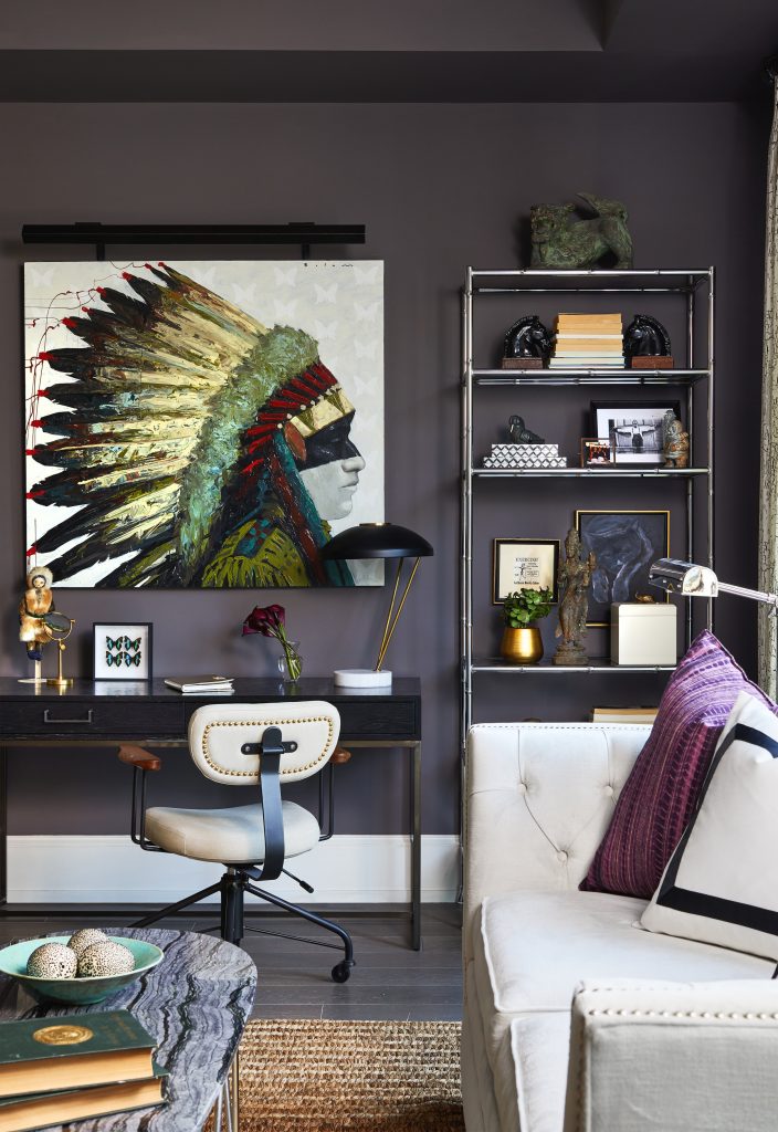 Home office corner in living room with desk, chair, shelfs and a picture with Native American