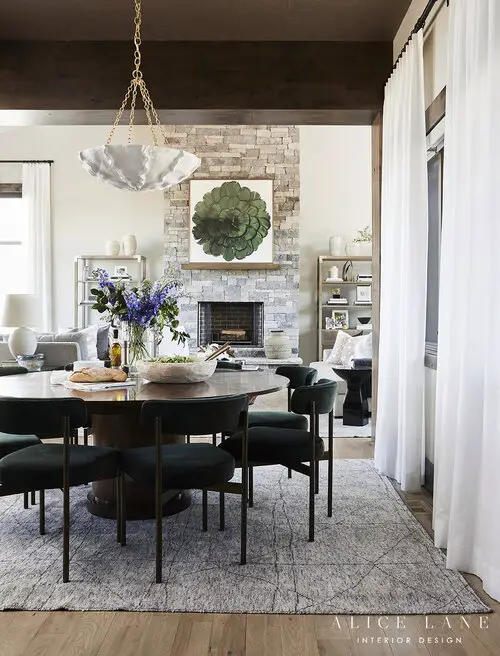 Dinning space with dark, round table and chairs and living room in the background