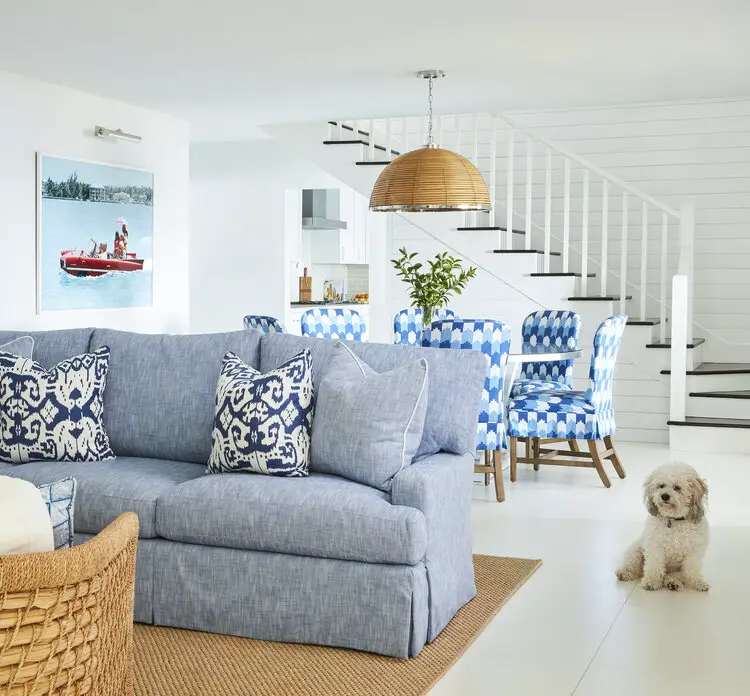 Living room with dinning space, with couch, dinning table, chairs, stairs in the background and dog beside the couch