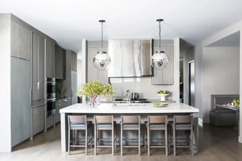 Designed kitchen with kitchen island, bar chairs, kitchen cabinet and lights