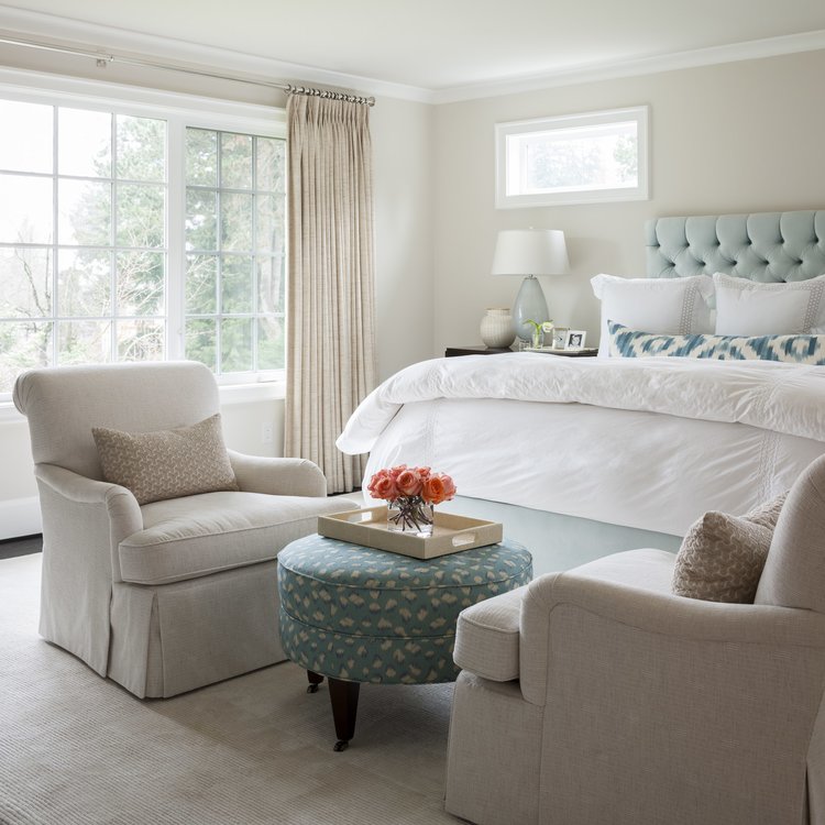 Bedroom with small table and armchairs in front of the double bed