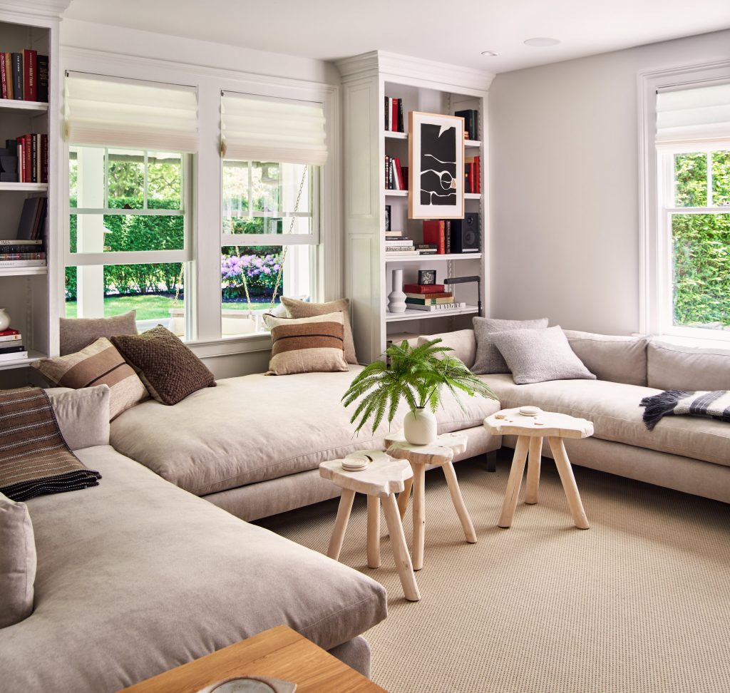 Living room with sofas and small wooden coffee tables with book shelfs behind the sofas