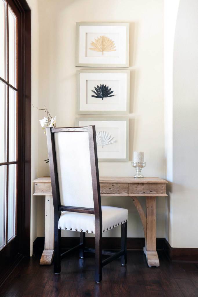 Corner of the room with desk, chair and  pictures above the desk hanging on the wall