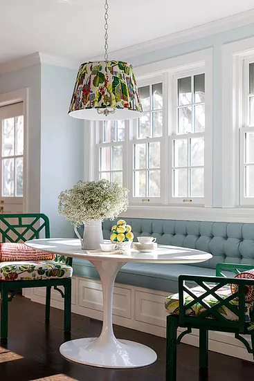 Dining space with bench, white table with flowers in the vase, with a pair of the chairs around the table