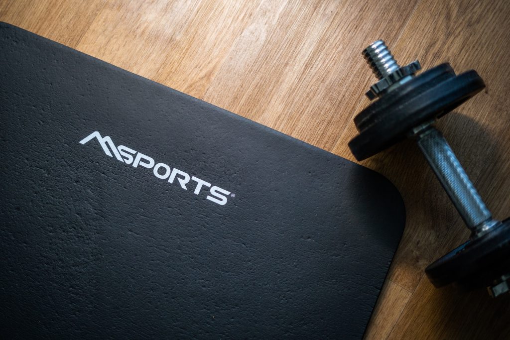 A black workout mat with a dumbbell beside