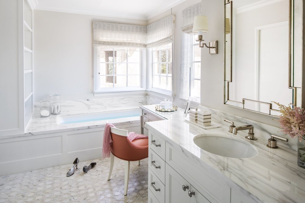 Master bathroom with bathtub, sink and a chair beside