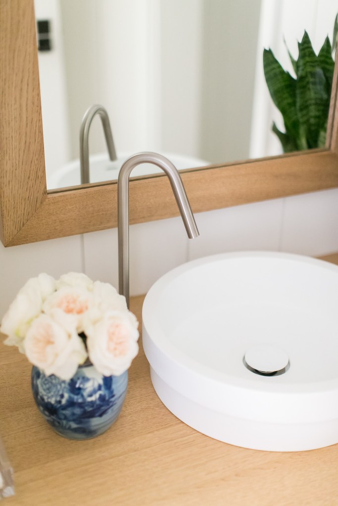 White sink with a vase with rose roses in the bathroom