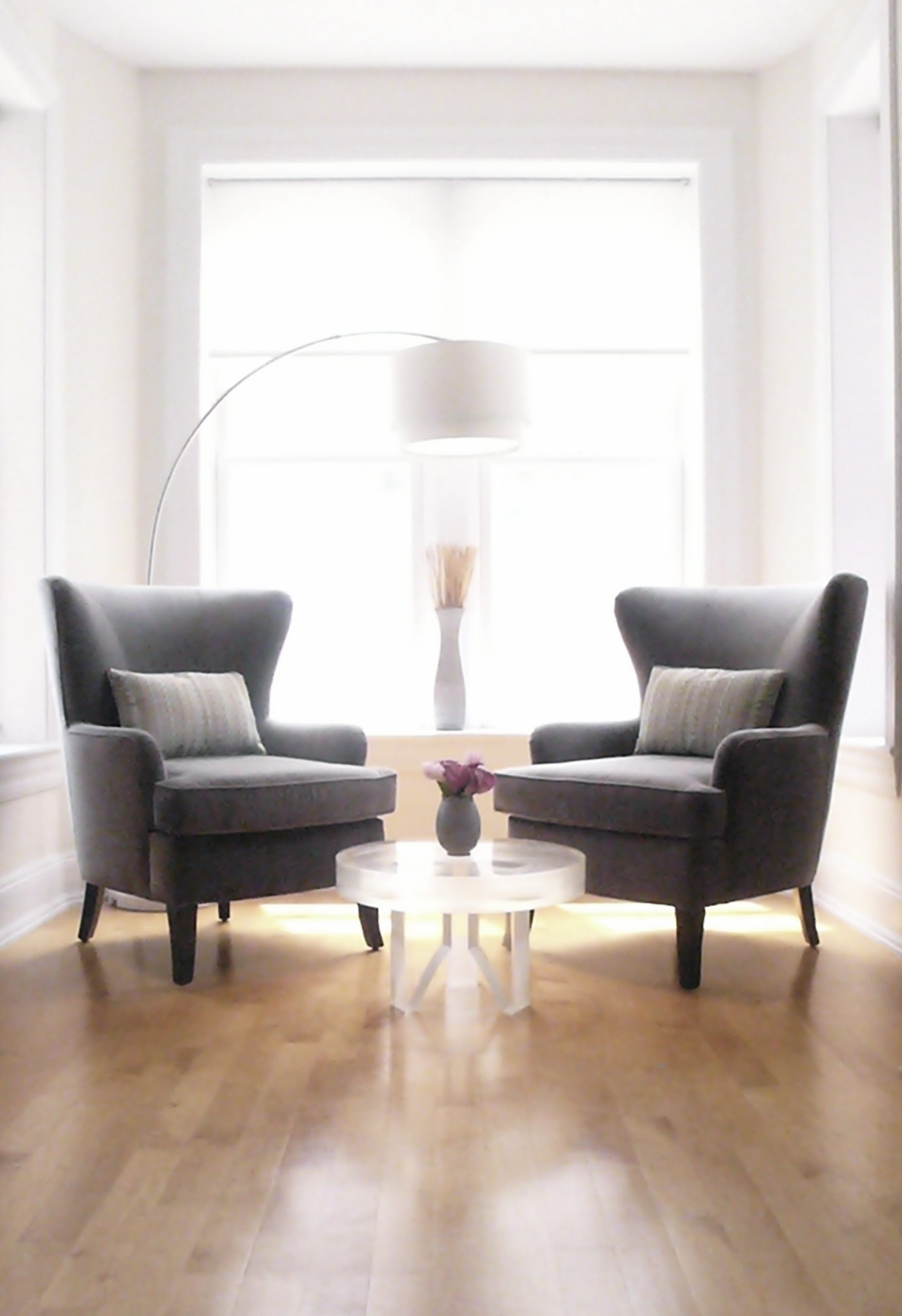 Two gray armchairs and small round table with window in the background in the office