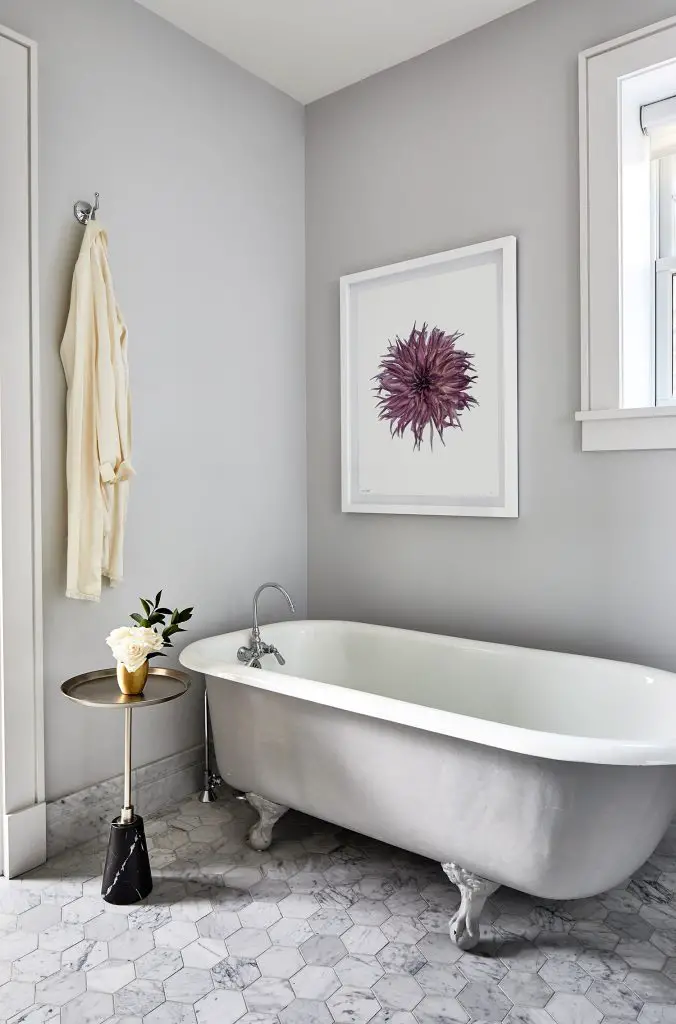 Bathroom with bathtub, image of the flower on the wall and a coffee table beside