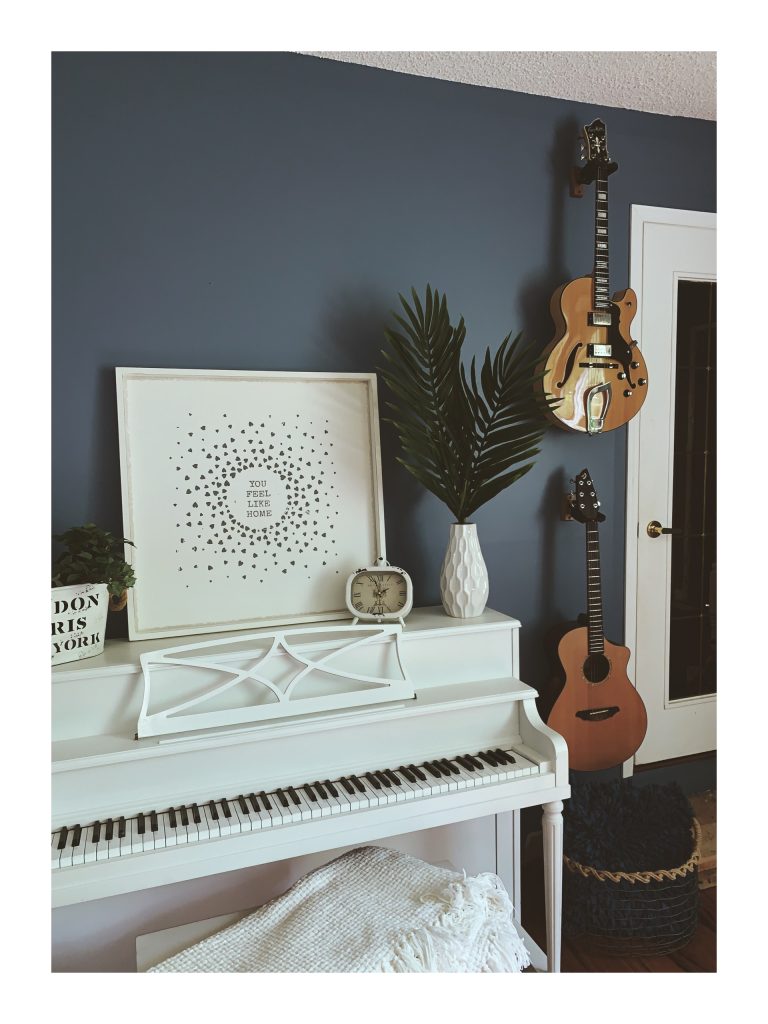 A white piano and two guitars in a music room