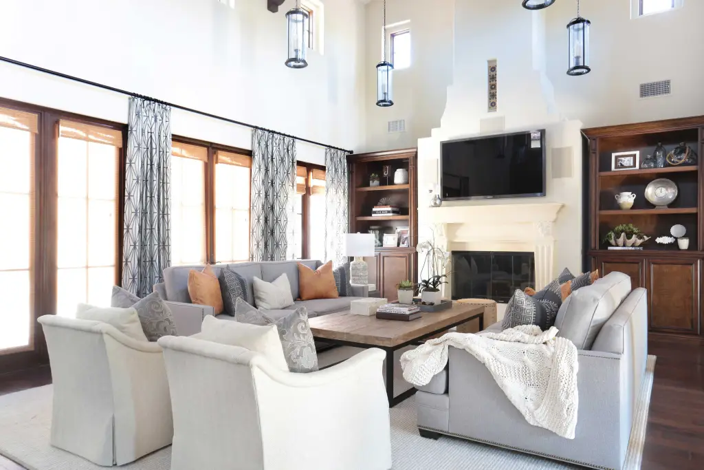 Living room with arm chairs, coffee table, TV and wide windows with curtains