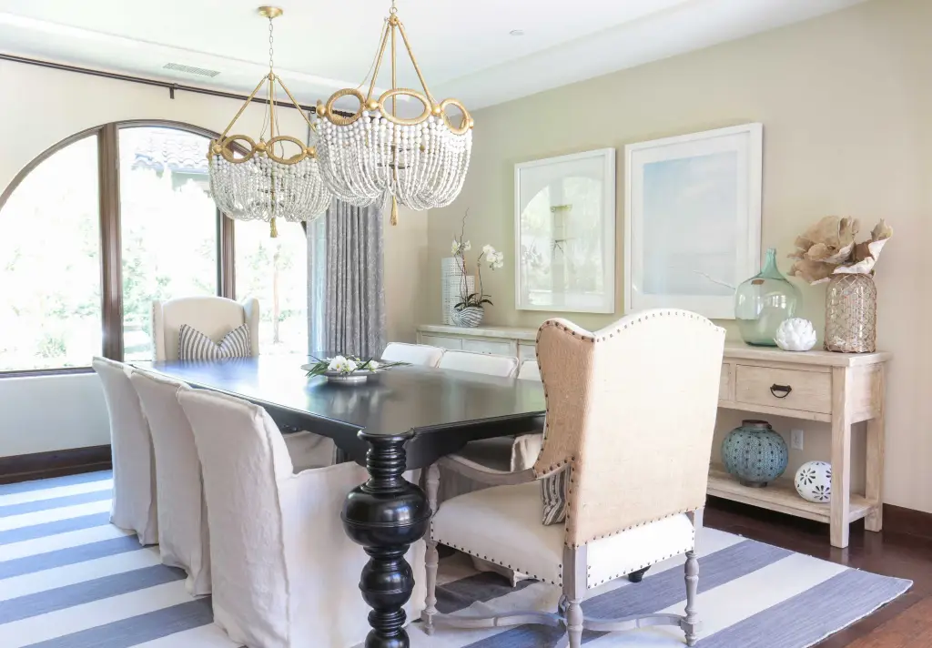 Dining space with black wooden table, white chairs and chandelier