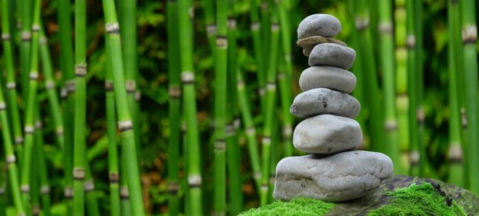Zen stones stacked on top of each other with bamboo in the background
