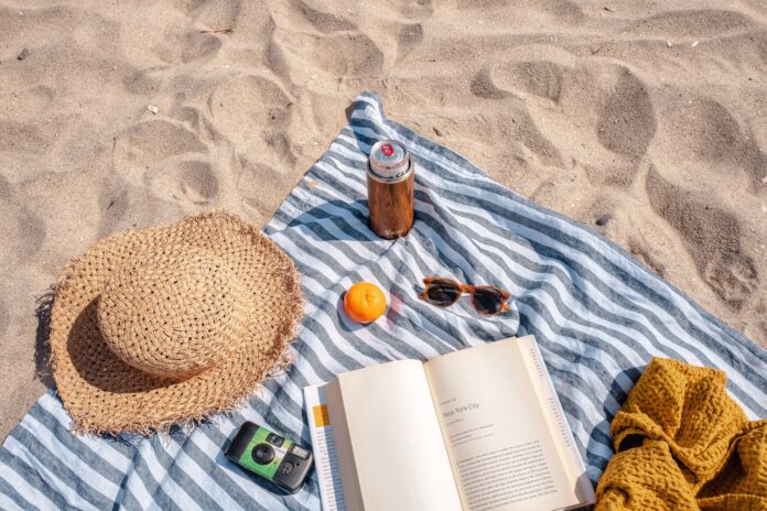 Towel, hat, sunglasses and book on the beach