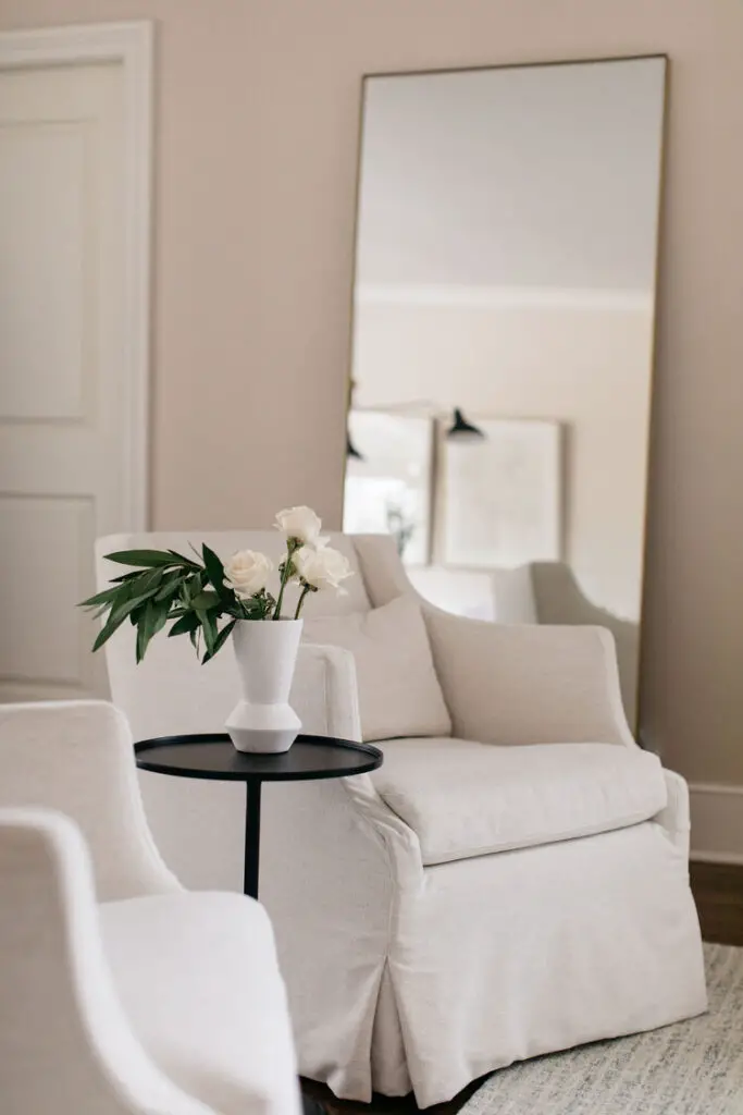 Two white armchairs and a black coffee table with a vase full of white roses
