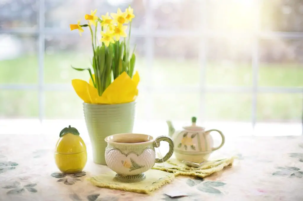 Table decoration with vase and yellow flowers, а cup and a teapot