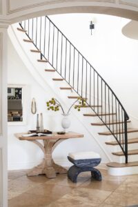 Hallway with stairs, wooden table and a black stool